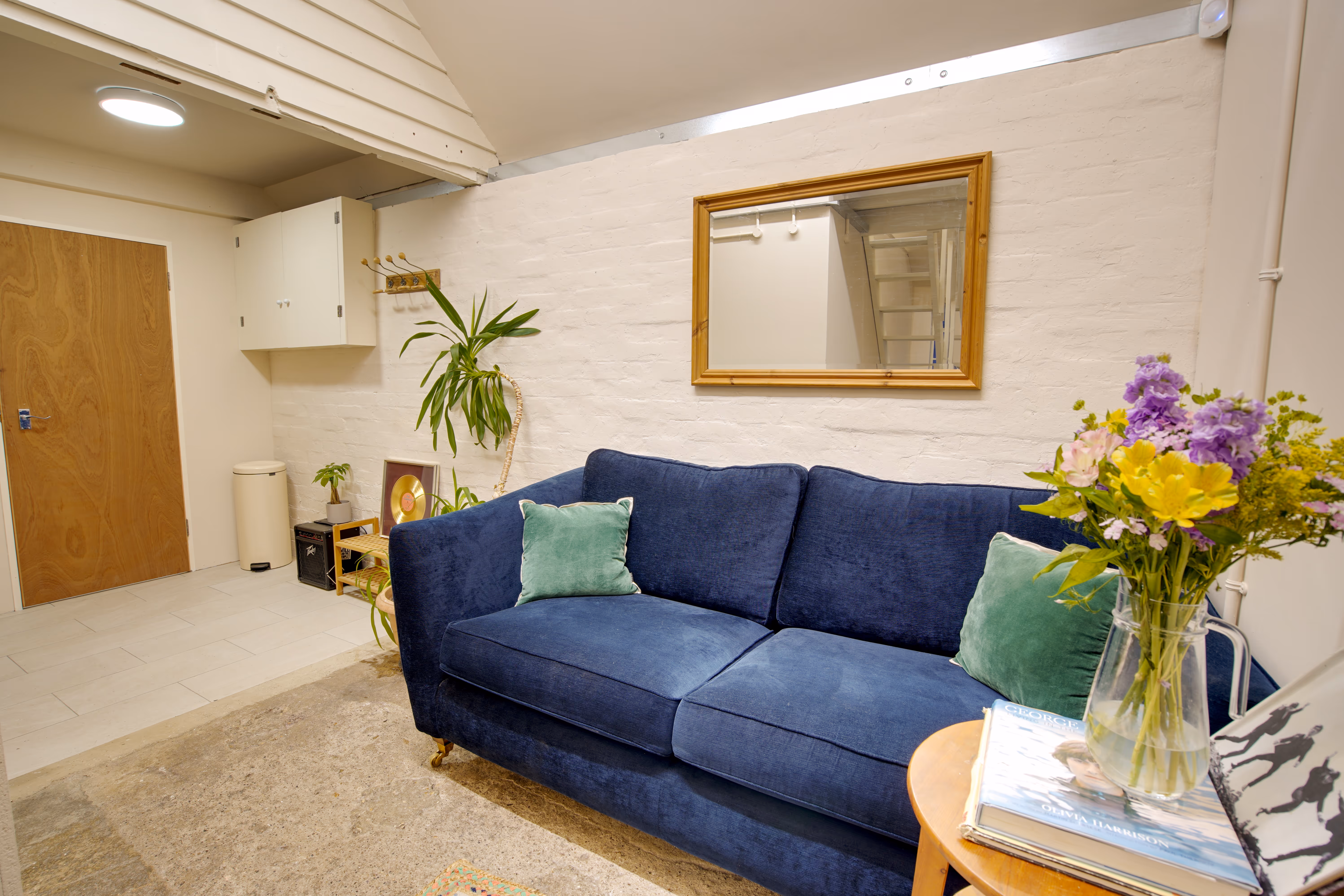 The lounge area — navy sofa, mirror, flowers, plants.