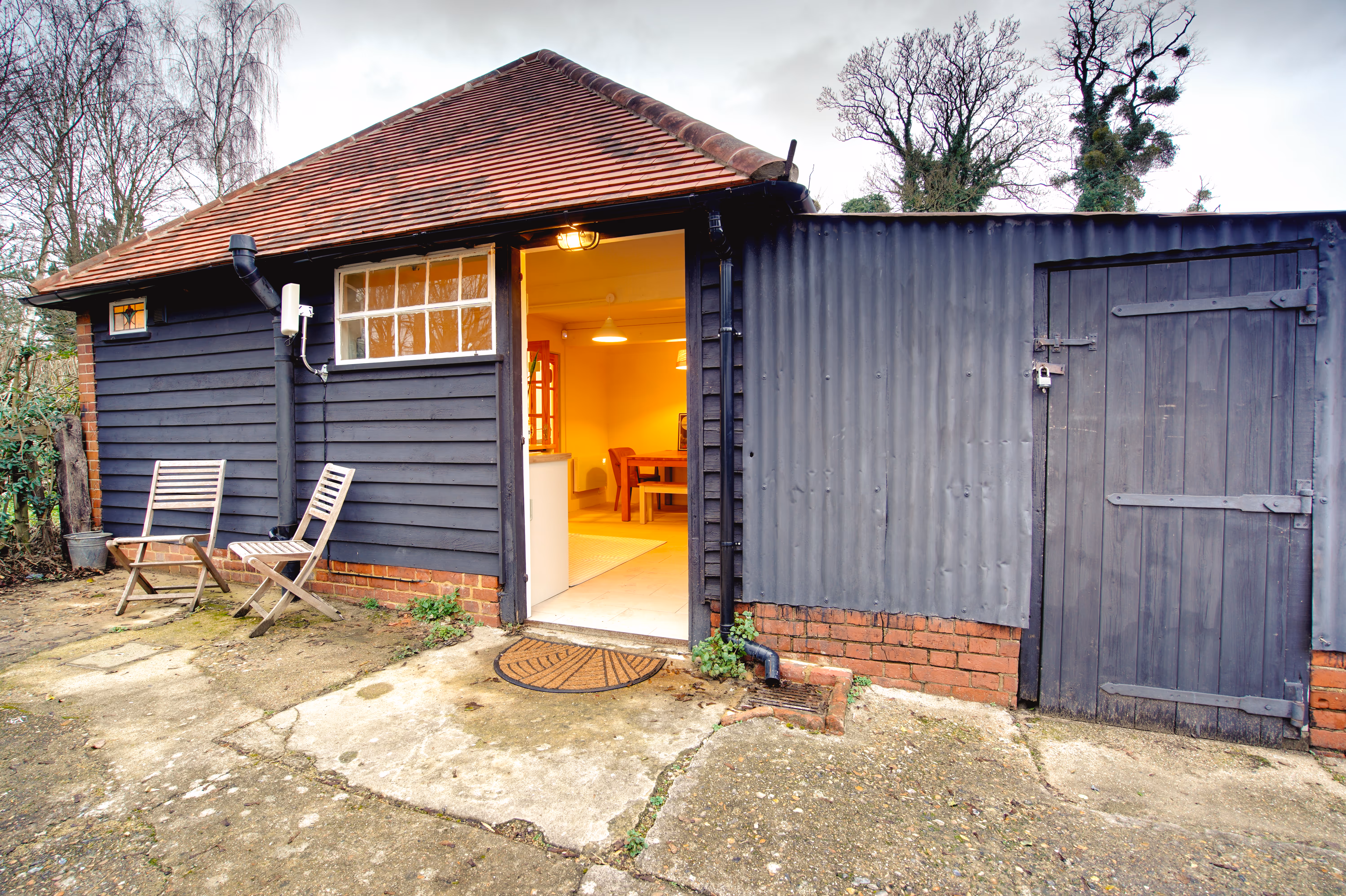 The back of the studio — black timber cladding, doors open to the garden.