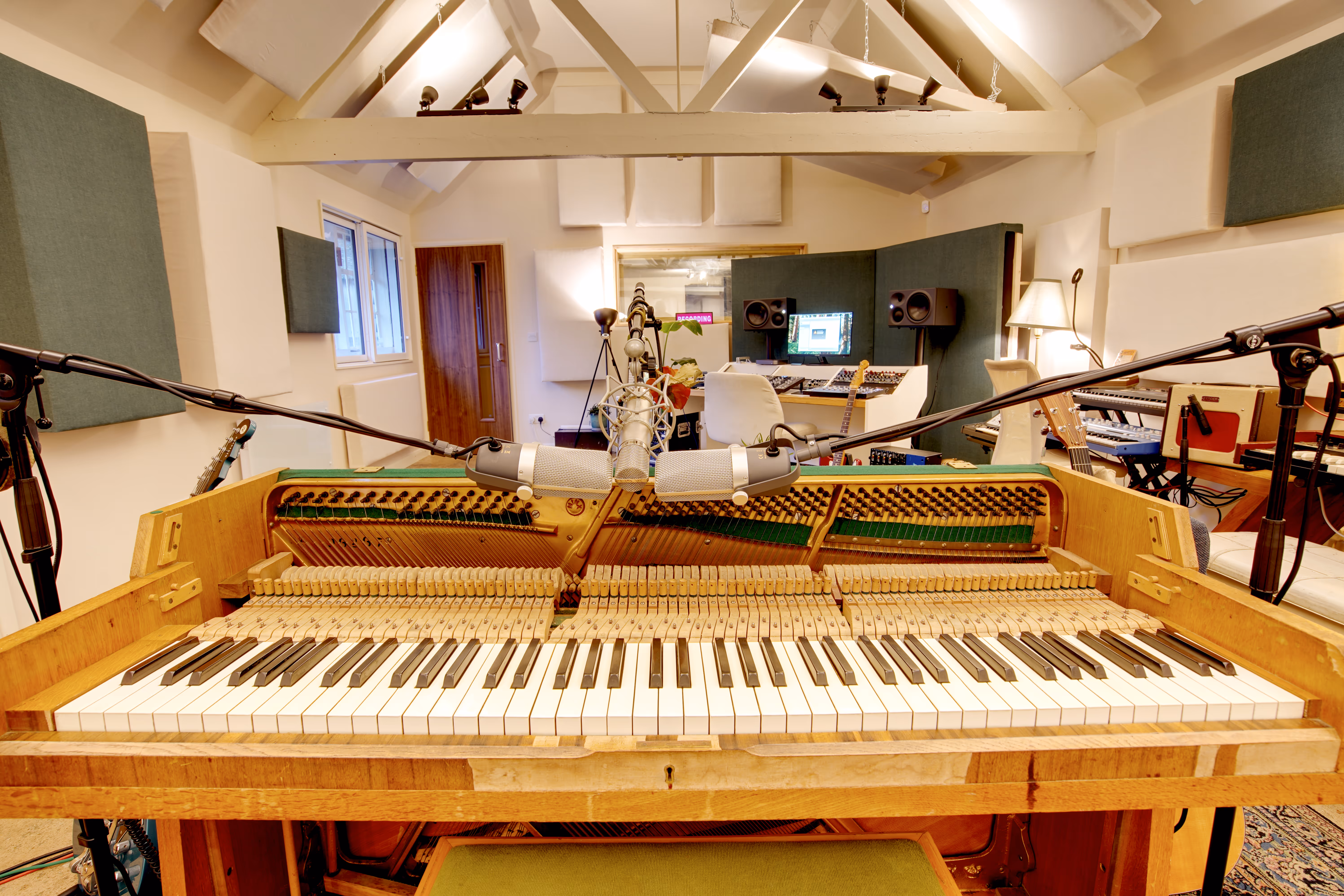 A vintage upright piano with mics positioned over the strings.